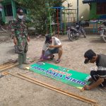 Anggota Satgas TMMD 110 Bojonegoro Membantu Warga Menata Banner